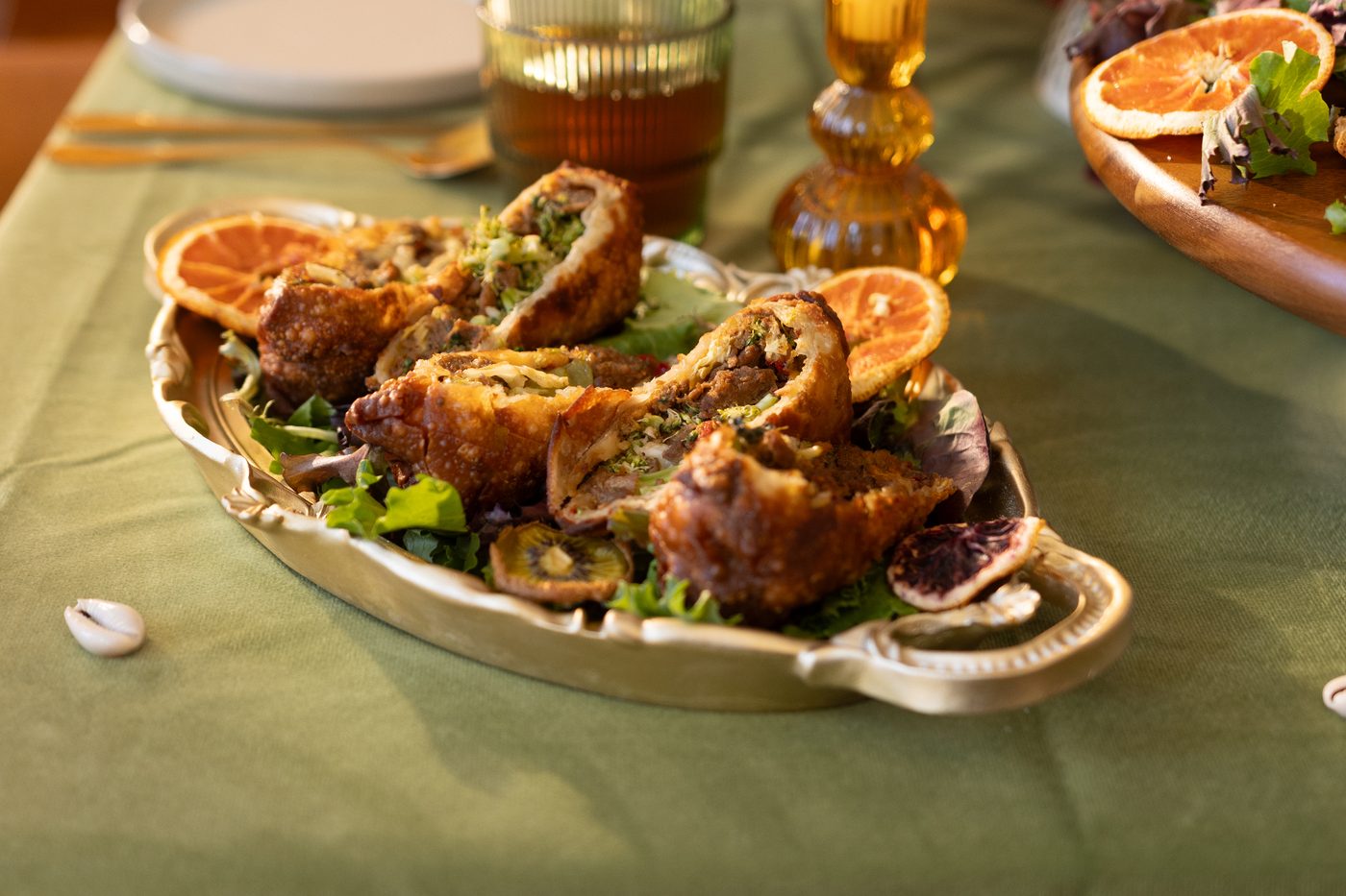 Fried pastries and dried citrus on a brass tray in warm light