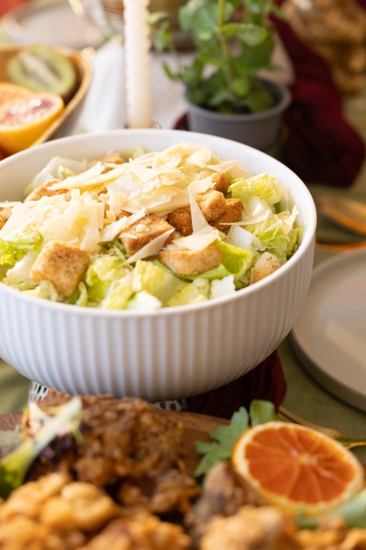 Caesar salad and shared platters on a green-clothed table