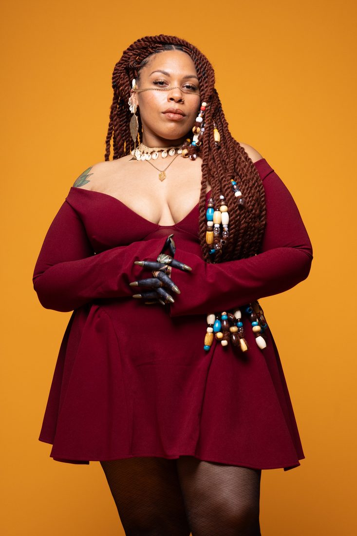 Chef Nefe in a burgundy dress against an amber backdrop